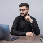 un homme assis à un bureau avec un ordinateur portable et un globe