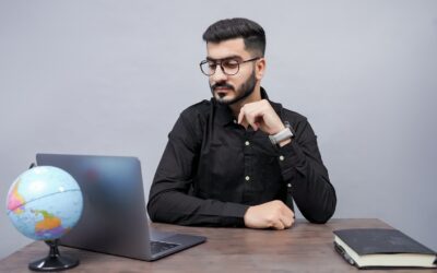 un homme assis à un bureau avec un ordinateur portable et un globe
