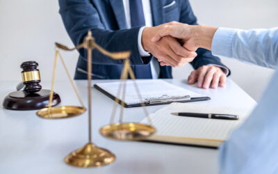 Poignée de main chaleureuse entre un conseiller juridique et un entrepreneur pour valider une création entreprise, avec une balance de la justice sur la table