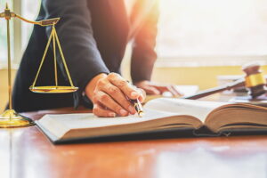 Professionnel du droit consultant un ouvrage juridique avec une balance de la justice, idéal pour un avocat à Belley.
