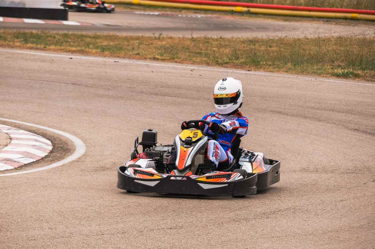Un conducteur en kart sur circuit, portant casque blanc, en pleine virage