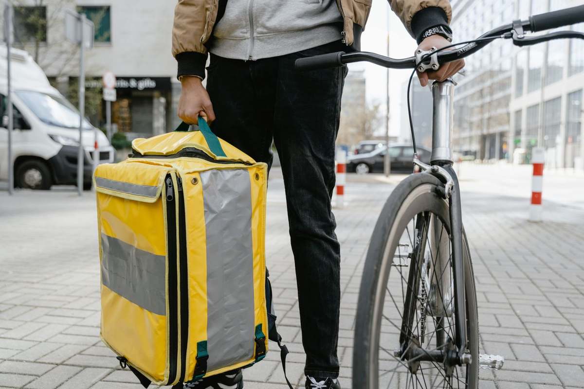 Personne avec sac jaune et vélo noir sur trottoir urbain Personne avec sac jaune et vélo noir sur trottoir urbain