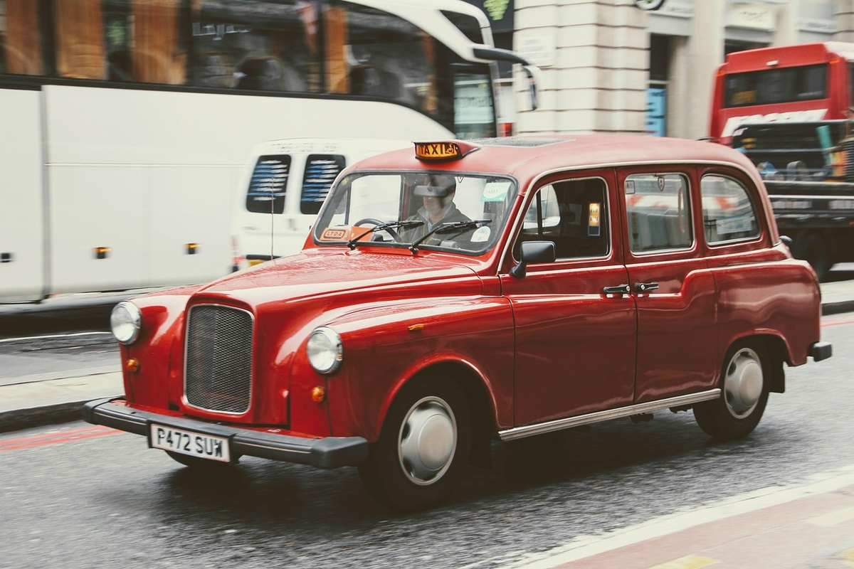 Taxi londonien rouge circulant en rue urbaine avec plaque de taxi éclairée Taxi londonien rouge circulant en rue urbaine avec plaque de taxi éclairée