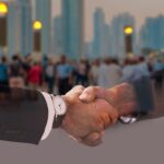 Deux hommes d'affaires en costume se serrent la main, gratte-ciel en arrière-plan