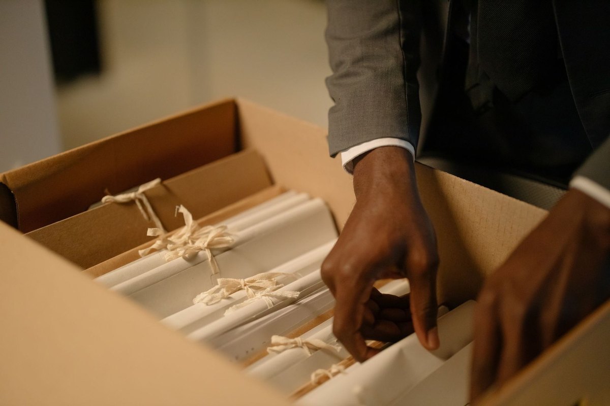 Une personne dénoue des rouleaux de papier dans une boîte en carton Une personne dénoue des rouleaux de papier dans une boîte en carton
