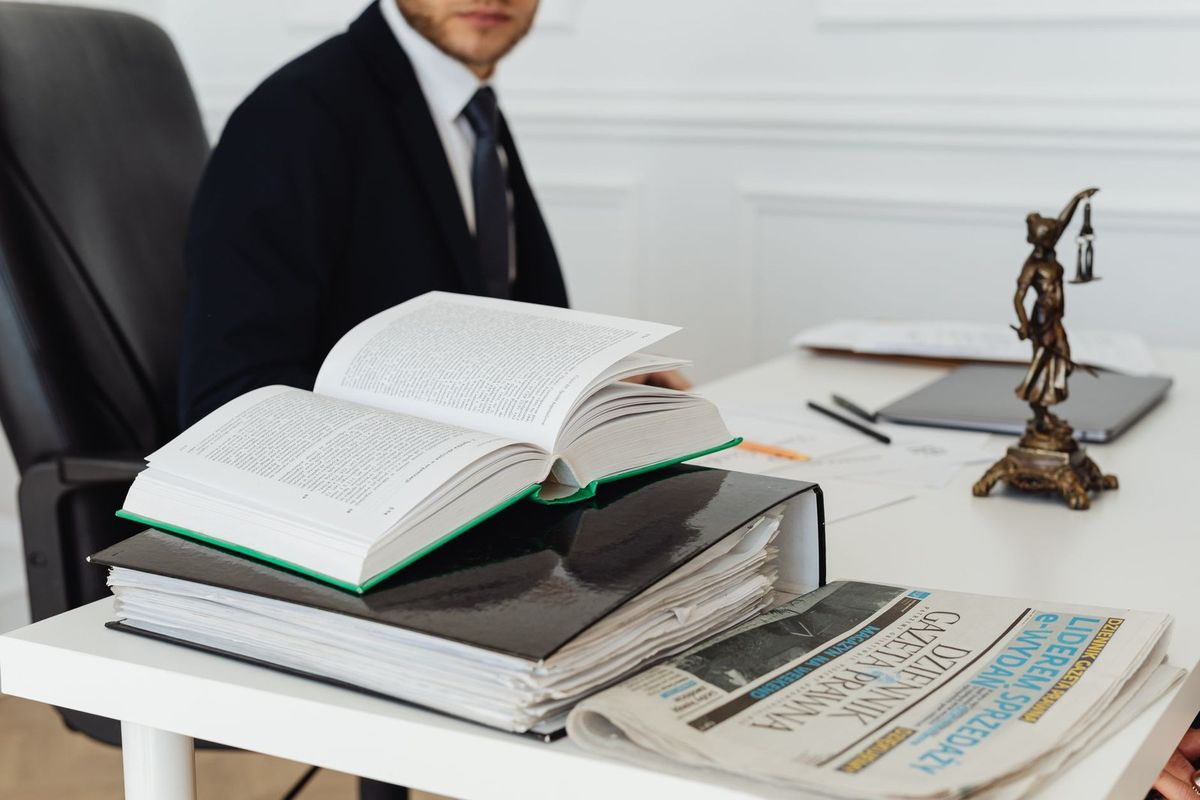 Bureau avec livre ouvert, documents, statue de justice, personne en costume, environnement de bureau Bureau avec livre ouvert, documents, statue de justice, personne en costume, environnement de bureau