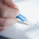 Main tenant un stylo bleu, en train de signer un document
