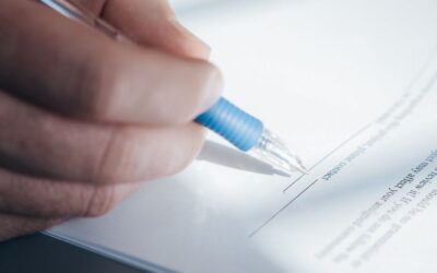 Main tenant un stylo bleu, en train de signer un document