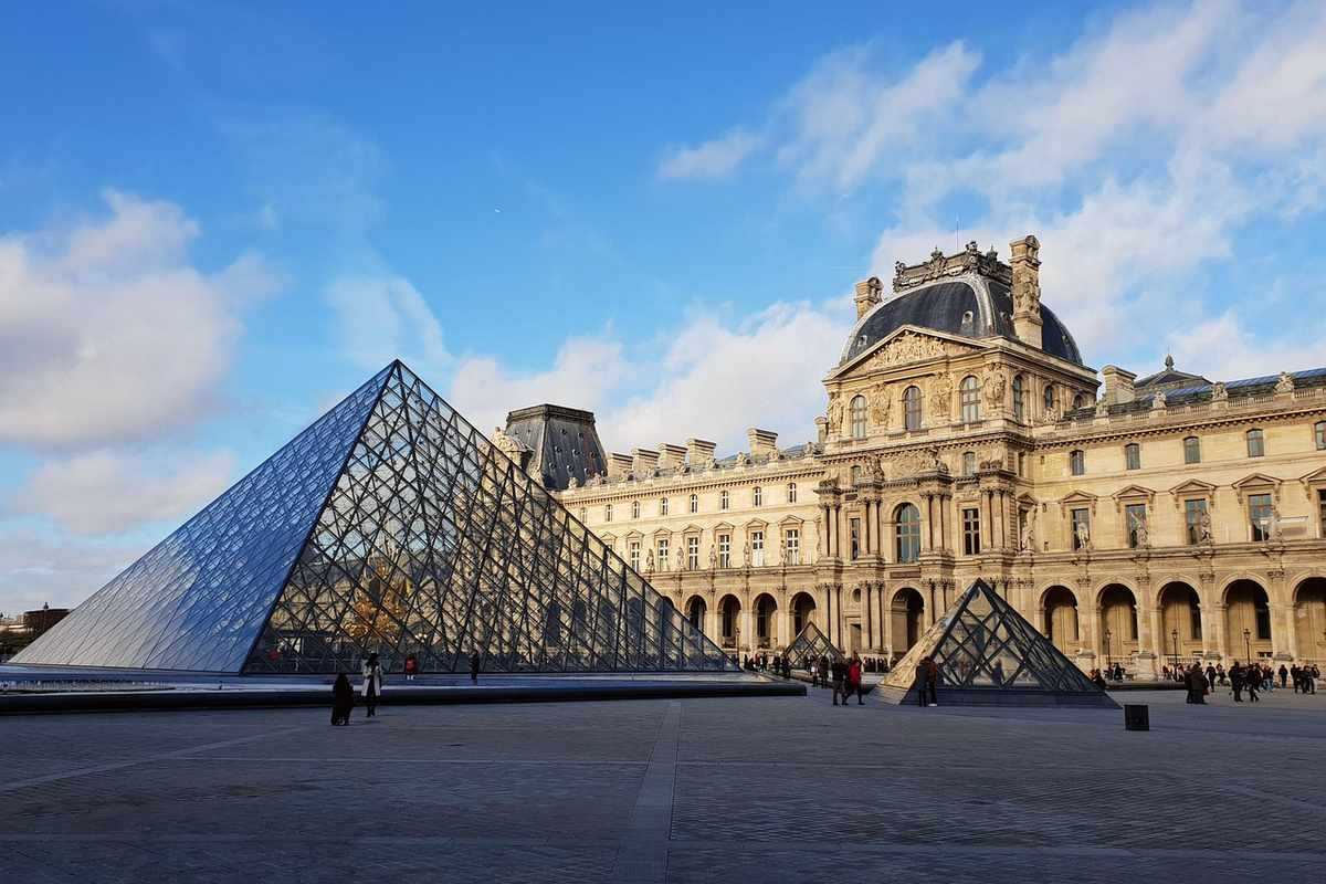 Cour intérieure du Louvre avec sa pyramide de verre moderne et le palais classique en arrière-plan Cour intérieure du Louvre avec sa pyramide de verre moderne et le palais classique en arrière-plan