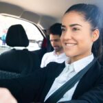 Une femme en costume conduit une voiture avec un passager à l'arrière