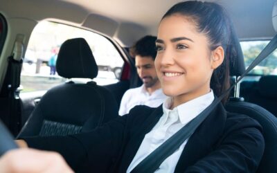 Une femme en costume conduit une voiture avec un passager à l'arrière