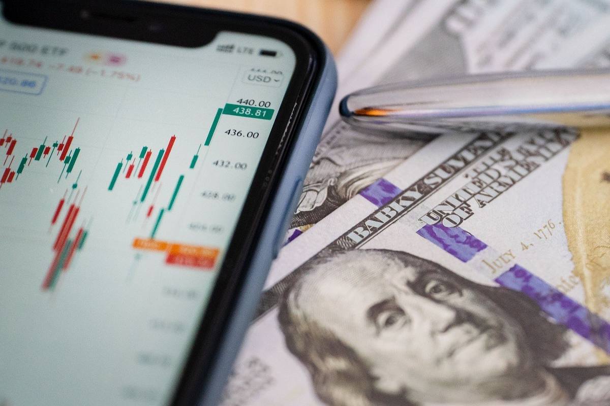 Smartphone montre graphique boursier, stylo et billets de 100 dollars Smartphone montre graphique boursier, stylo et billets de 100 dollars