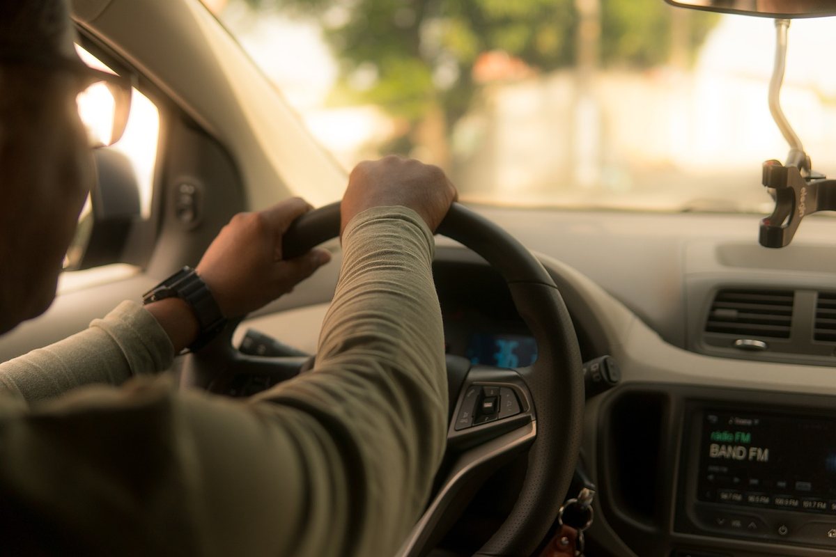 Un conducteur tient le volant à l'intérieur d'une voiture, radio allumée Un conducteur tient le volant à l'intérieur d'une voiture, radio allumée
