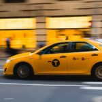 Un taxi jaune roule rapidement sur une rue urbaine