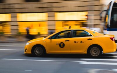 Un taxi jaune roule rapidement sur une rue urbaine