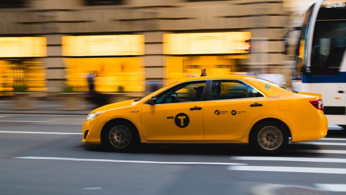 Un taxi jaune roule rapidement sur une rue urbaine
