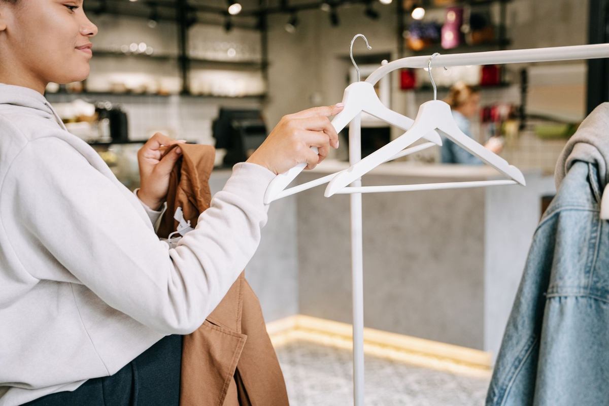 Femme sélectionne un vêtement sur un rack dans une boutique Femme sélectionne un vêtement sur un rack dans une boutique