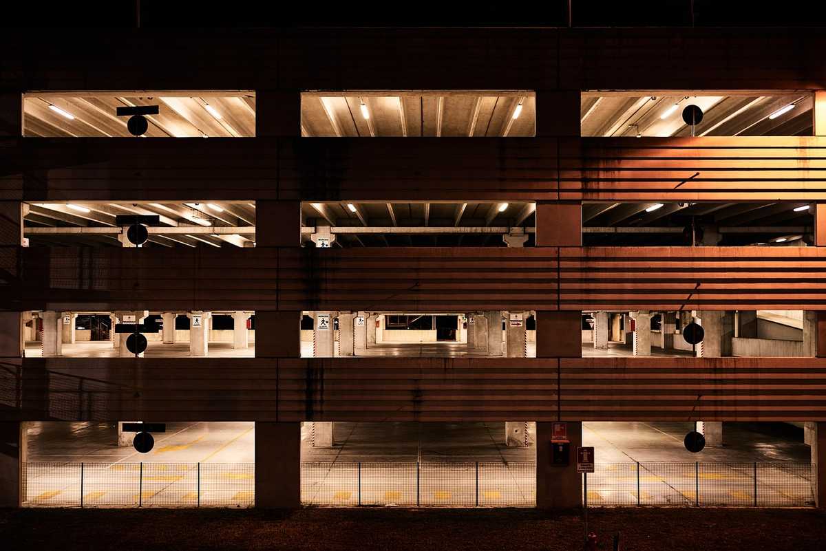 Vue nocturne d'un parking multi-étages éclairé, colonnes et voitures