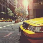 Plusieurs taxis jaunes garés dans une rue de ville avec bâtiments et arbres