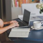 Une femme travaille à distance, tapant sur ordinateur, avec café et notes