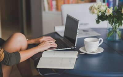 Une femme travaille à distance, tapant sur ordinateur, avec café et notes