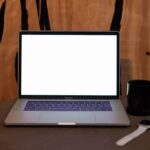 Un ordinateur portable ouvert sur une table avec une tasse et une montre