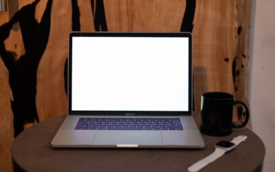 Un ordinateur portable ouvert sur une table avec une tasse et une montre