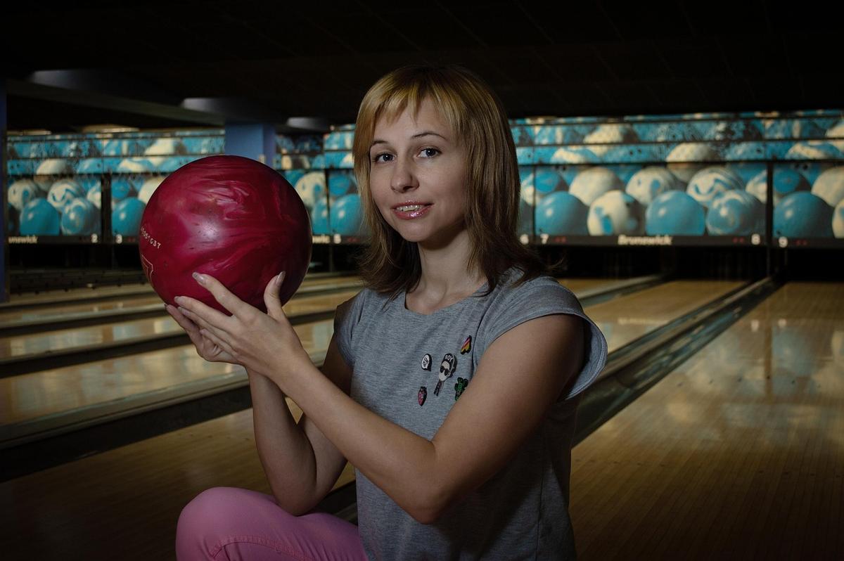 Une femme assise, tenant une boule rouge, prête à lancer Une femme assise, tenant une boule rouge, prête à lancer