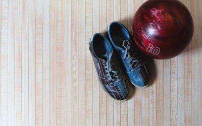 Chaussures de bowling et boule rouge posés sur sol strié